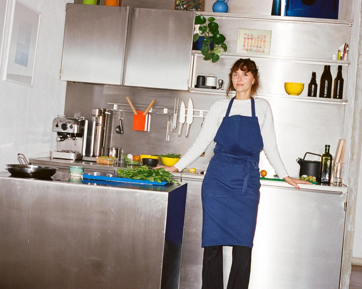 Person wearing a blue apron in a kitchen setting